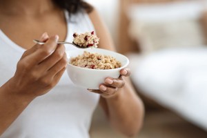 A woman holding a bowl of oatmeal after wisdom tooth removal